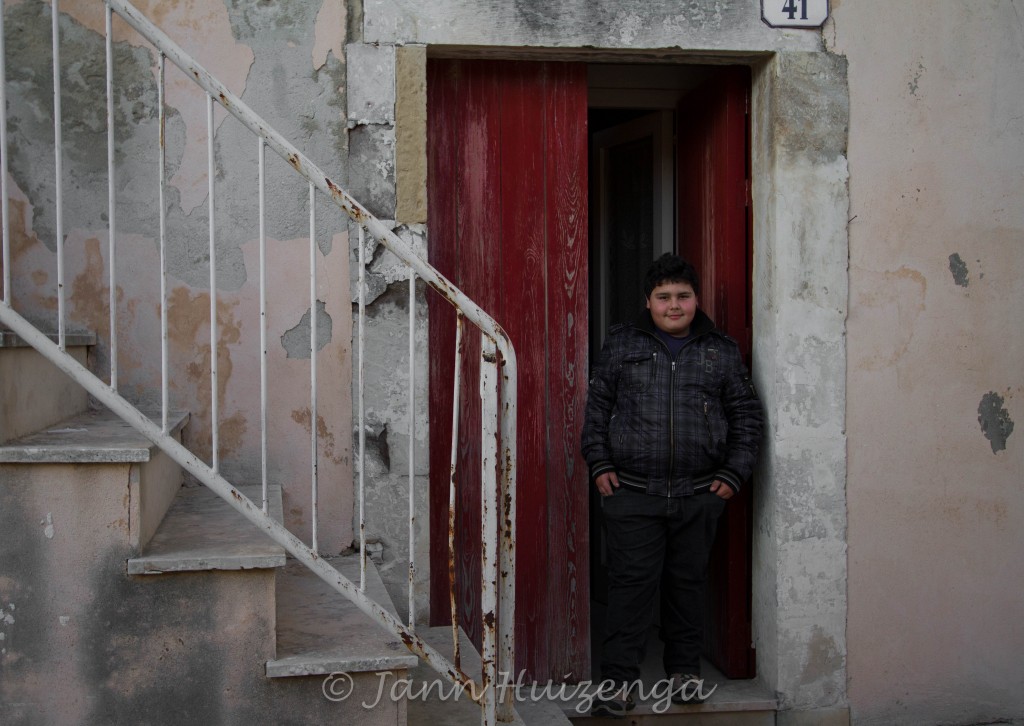 Sicilian boy in front of red doors, copyright Jann Huizenga